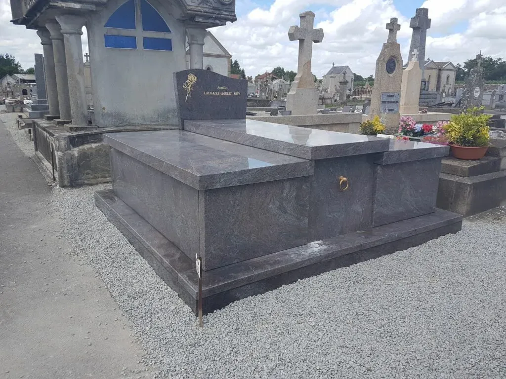 Grand monument funéraire en granit gris poli installé dans un cimetière.